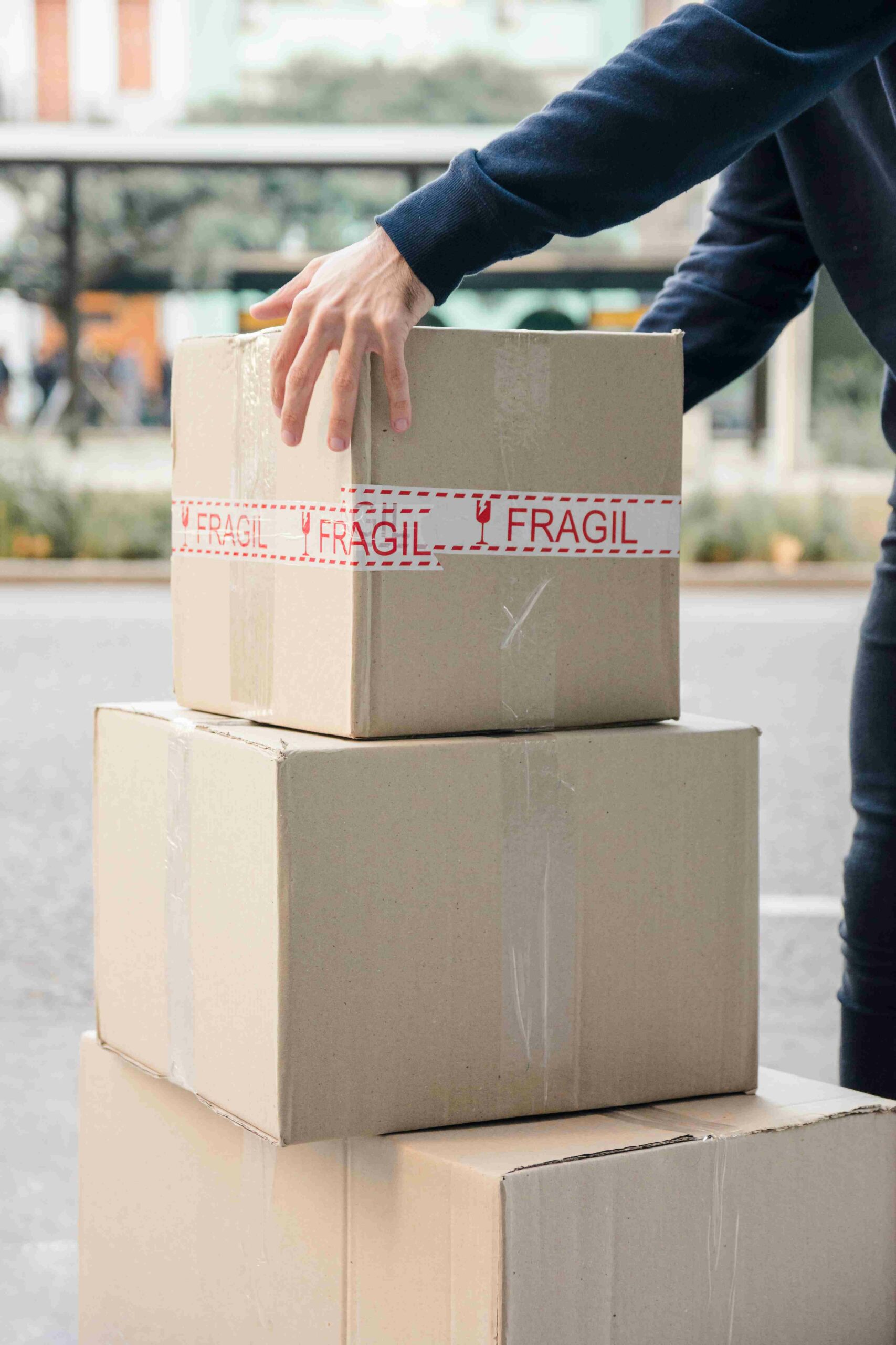 close-up-delivery-man-s-hand-picking-up-cardboard-box_11zon